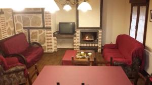 a living room with red chairs and a fireplace at La plazuela Navaluenga in Navaluenga