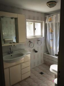 een badkamer met een wastafel, een toilet en een raam bij Oikia Ahanasia in Karlovasi