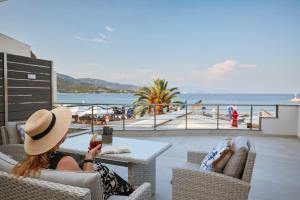 a woman in a hat sitting at a table looking at her cell phone at Horizon Seaside Living in Iraklitsa