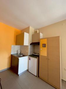 a small kitchen with a white refrigerator and cabinets at Rooms Elena in Nea Potidaea +37 photos