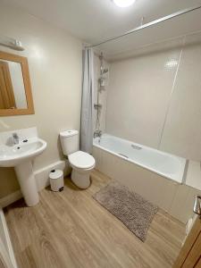a bathroom with a sink and a toilet and a bath tub at Barchester House Apartments in Salisbury