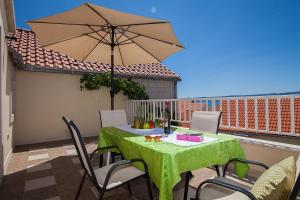 a table and chairs with an umbrella on a balcony at Aurora Apartments in Bol
