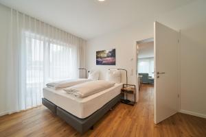 a white bedroom with a bed and a mirror at Parkblick Bad Driburg in Bad Driburg