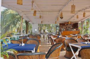un restaurante vacío con mesas y sillas y un registrador en Arabian Sea Beach Resort en Morjim