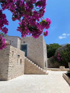 un edificio de piedra con escaleras y flores púrpuras en Mainotti's house, en Areopoli