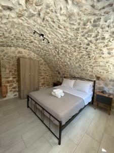 a bedroom with a bed and a stone wall at Mainotti's house in Areopoli