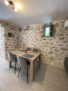 una mesa de madera y sillas en una habitación con una pared de piedra en Mainotti's house, en Areopoli