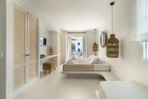 - une chambre blanche avec 2 lits et une table dans l'établissement Andros Utopia, à Batsi