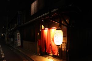 
a man standing in front of a door at night at Guesthouse KYOTO COMPASS in Kyoto
