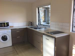 a kitchen with a sink and a washing machine at Golfcourse Road Chalets and Lodge in Wanaka