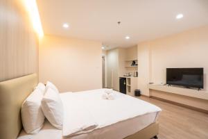 een slaapkamer met een wit bed en een flatscreen-tv bij Oriole Residence - Suvarnabhumi in Ban Khlong Thewa