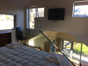 1 dormitorio con 1 cama y TV de pantalla plana en Golfcourse Road Chalets and Lodge en Wanaka