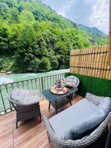 eine Terrasse mit einem Tisch und Stühlen sowie Flussblick in der Unterkunft Elegant Bungalov in Rize