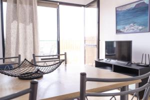 a dining room with a table with chairs and a television at Piso Dunas Blu - Carpe Mundi in Corralejo