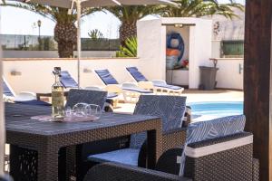 a table and chairs with a bottle of wine on it at Villa Sosha - Carpe Mundi in La Oliva