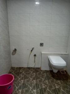 a bathroom with a toilet and a pink bucket at TRI HOTEL in Mumbai