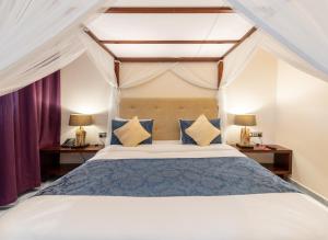 1 dormitorio con 1 cama con almohadas azules y amarillas en Muthu Sovereign Suites & Spa, Limuru Road, Nairobi en Limuru