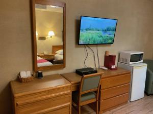 シェルブルックにあるMotel & Hotel La Paysanneのデスク、テレビ、鏡が備わる客室です。