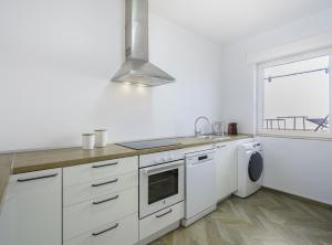 eine weiße Küche mit einem Herd oberer Ofen neben einem Fenster in der Unterkunft SibsBcn-Paseo de Gracia Penthouse-Luxury-Terraces in Barcelona