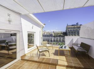 einen Balkon mit Stühlen und einem Tisch auf einem Gebäude in der Unterkunft SibsBcn-Paseo de Gracia Penthouse-Luxury-Terraces in Barcelona