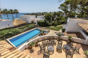 un patio con sillas y una piscina en La Chamade Cala DOr, en Cala Santanyi