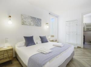 ein weißes Schlafzimmer mit einem Bett mit Handtüchern darauf in der Unterkunft SibsBcn-Paseo de Gracia Penthouse-Luxury-Terraces in Barcelona
