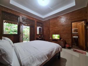 a bedroom with a white bed and a television at La Tavisa Hotel Borobudur in Magelang