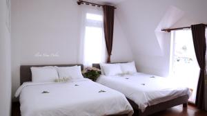 two beds in a room with two windows at FLORA HOME DALAT in Da Lat