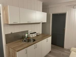 cocina con fregadero, armarios blancos y puerta en Willa Anna, en Gródek Nad Dunajcem