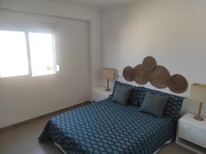 een slaapkamer met een bed met een blauw dekbed en een raam bij Apartamento Campoamor in Castellón de la Plana