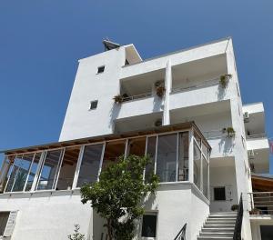 a white apartment building with large windows and stairs at Joni Apartments in Ksamil