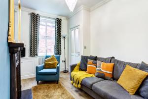 uma sala de estar com um sofá cinzento e uma cadeira azul em Woodside Cottage, Congleton, Nr Peak District em Congleton