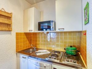 a kitchen with a stove and a sink and a tv at Apartment Ariane-3 by Interhome in Le Corbier