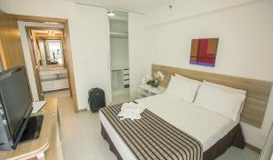 ein Hotelzimmer mit einem Bett und einem TV in der Unterkunft Biarritz Hplus Long Stay in Brasilia