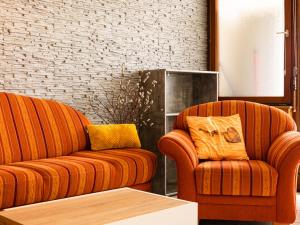 zwei orangefarbene Sofas im Wohnzimmer in der Unterkunft Apartment G 25 by Interhome in Dittishausen