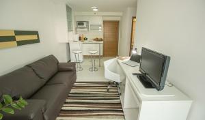 a living room with a couch and a television on a desk at Biarritz Hplus Long Stay in Brasilia