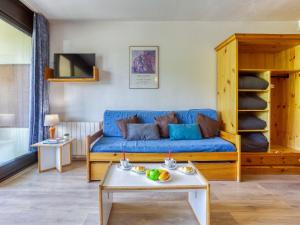 a living room with a blue couch and a table at Studio Cosmos-1 by Interhome in Le Corbier