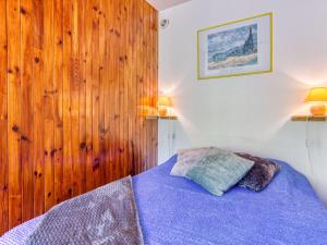 a bedroom with a blue bed with wooden walls at Studio Cosmos-1 by Interhome in Le Corbier