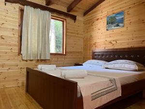 1 dormitorio con 1 cama en una cabaña de madera en Bujtina Llogara, Log Cabins, en Vlorë