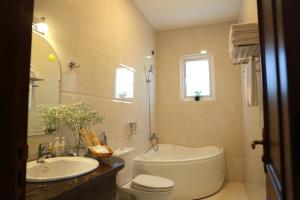 a bathroom with a tub and a toilet and a sink at FLORA HOME DALAT in Da Lat