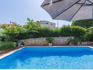 een zwembad met een parasol naast een muur bij Apartment Romantika-2 by Interhome in Štanga