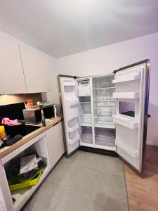 een open koelkast met de deur open in een keuken bij LES RÉSIDENCES DE DJIBRIL in Le Blanc-Mesnil