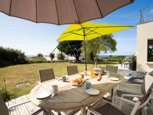 a wooden table with a yellow umbrella on a patio at Holiday Home Hidel - TRP101 by Interhome in Plouarzel