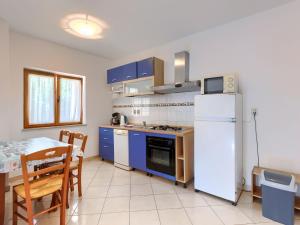 een keuken met blauwe kasten en een witte koelkast bij Apartment Romantika-2 by Interhome in Rovinj