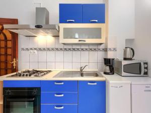 a kitchen with blue cabinets and a sink and a microwave at Apartment Romantika - ROJ108 by Interhome in Rovinj