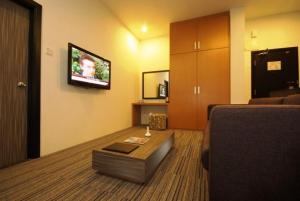 sala de estar con sofá y TV en la pared en Flemington Hotel, en Taiping