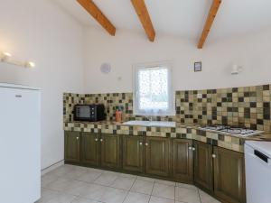 een keuken met houten kasten, een wastafel en een raam bij Holiday Home Brive 2 by Interhome in Pontaillac
