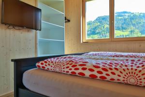 a bed with a red and white comforter and a window at Bergreich Appartement 3 in Schoppernau