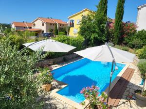 a swimming pool with two umbrellas in a yard at Apartments Grgic in Njivice