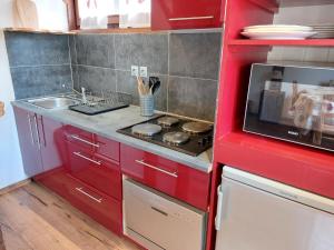 a red kitchen with a stove and a sink at Studio Castel des Roches-2 by Interhome in Saint-Gervais-les-Bains